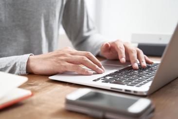 Colour photo of person typing on a laptop