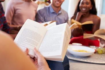 Colour photo of men and women sitting together reading 