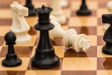 Black and White chess pieces on a wooden chess board 