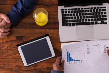 Two people sitting at a table with a laptop and business papers