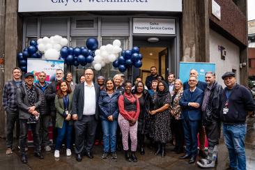 A group of people standing outside the Soho Estate office with white and blue balloons in the background 