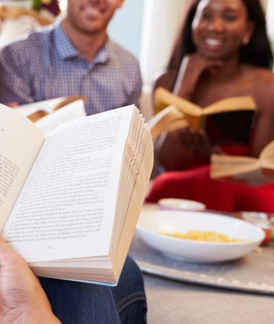 Colour photo of men and women sitting together reading 