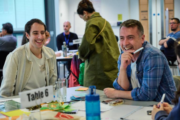 Image of two men sitting at a table smiling