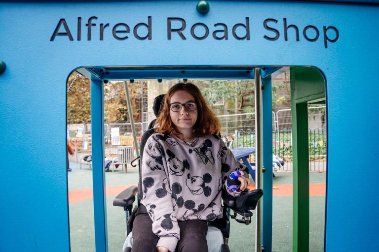 A young person is photographed under the climbing frame which has been designed to be tall enough for wheelchairs to fit under it..