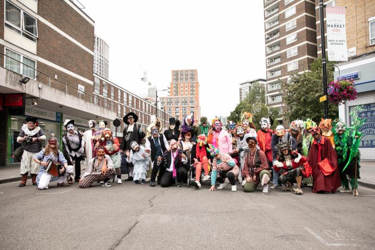 A group photo of the Dende Collective in costumes and masks at Church Street Market