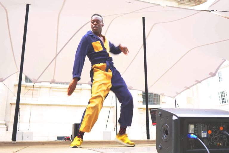 A dancer from Union Dance performing on stage in a gold and navy jumpsuit