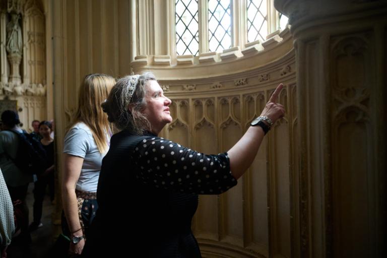 A woman pointing to the decorative stonework in westminster abbey