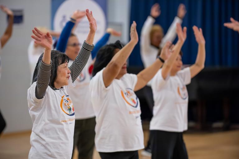 image of 3 women in white t-shirts with their arms and hands in the air