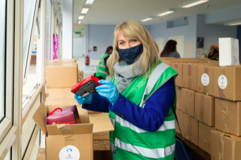 Westminster City Council volunteer wearing a green vest and making a hamper