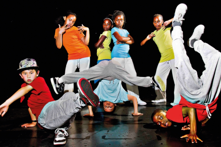 A group of young dancers posing against a black backdrop