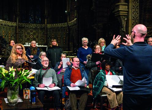 A conductor leading a choir of older people singing in a church