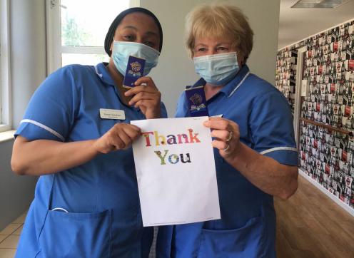 Two nurses holding up a sign that says 'Thank You'