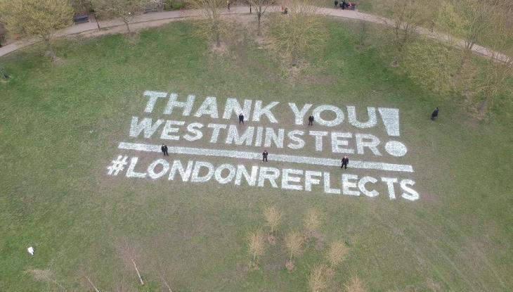 A sign in the grass of Paddington recreation ground that reads 'Thank you Westminster! #LondonReflects'